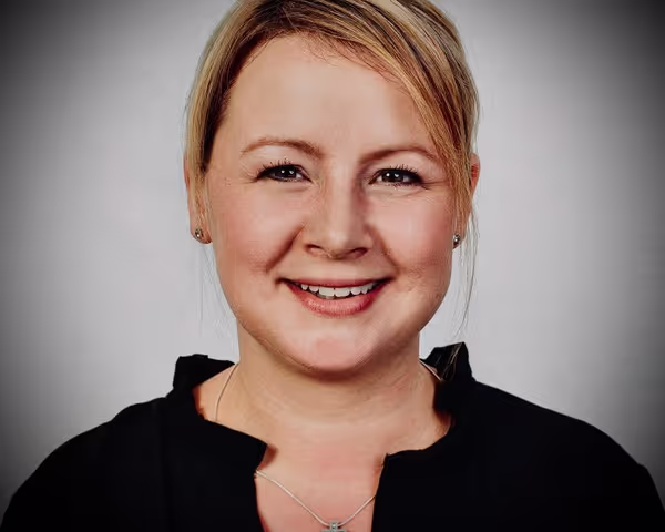 Woman with blond hair and black shirt is smiling into the camera
