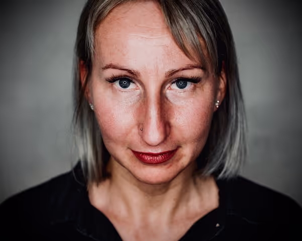 Woman with blond hair and diamond earring waring a black shirt and looking directly into the camera
