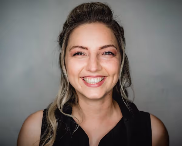 Woman with dark hair and blond highlights smiling into the camera