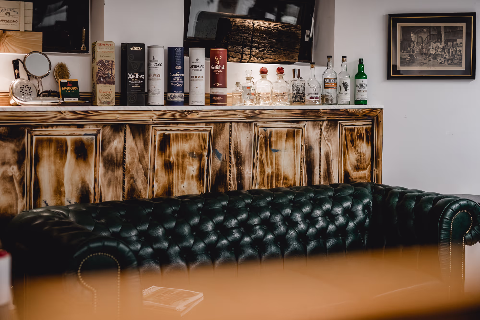 A black leather couch in front of a sideboard
