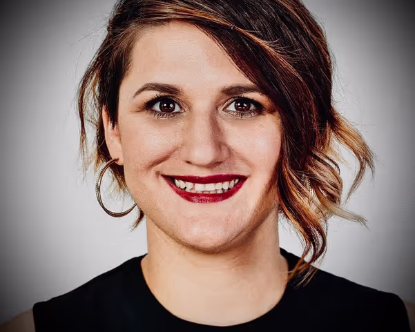 A young woman with red lipstick and brown hair smiling in the camera