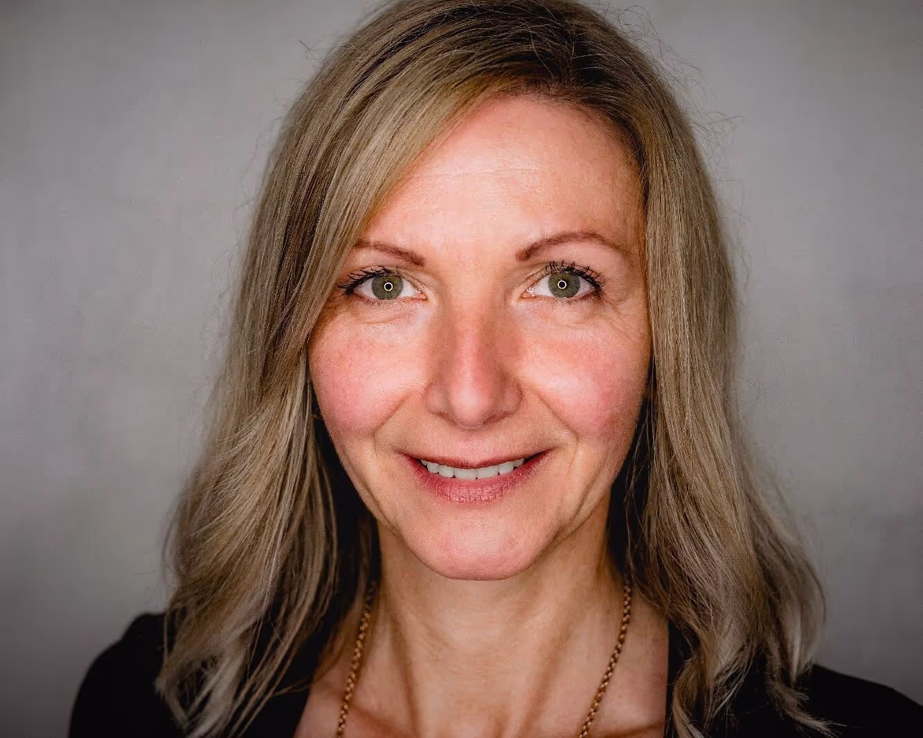 A blond lady in the age between 30 and 60, looking directly in the Camera
