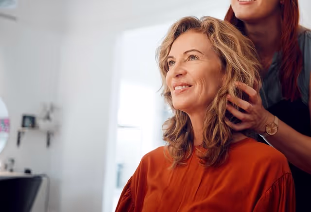 Older woman looking into a mirror while her hair is getting tended to